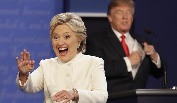 Hillary Clinton, sullo sfondo Donald Trump