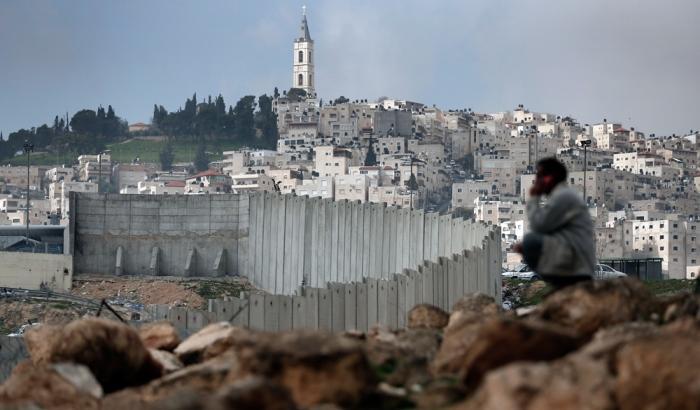 Un palestinese vicino al muro che separa il quartiere di Gerusalemme Est al Tur e la Cisgiordania