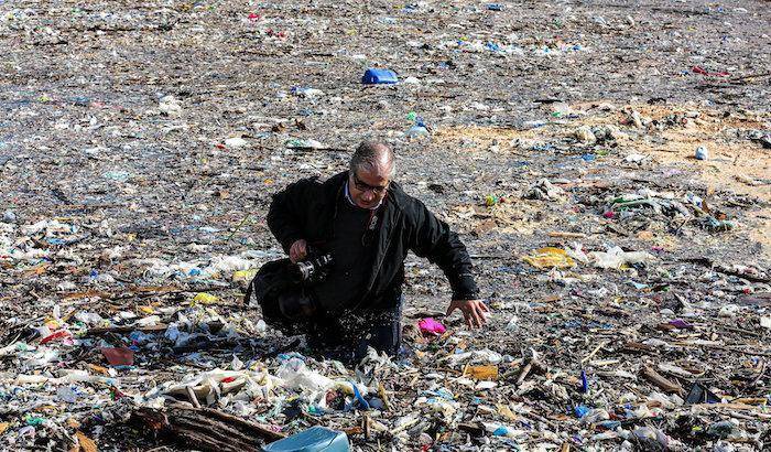 Un fotografo si fa strada nel mare di rifiuti