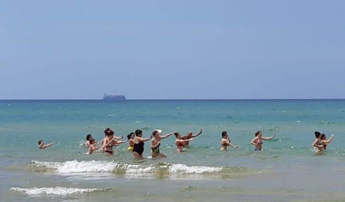 Pozzallo e l'indifferenza, balli di gruppo in spiaggia e sullo sfondo la Maersk